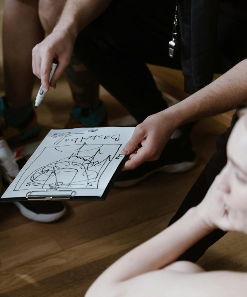 Close-up of a basketball team huddling with the coach discussing strategy indoors.